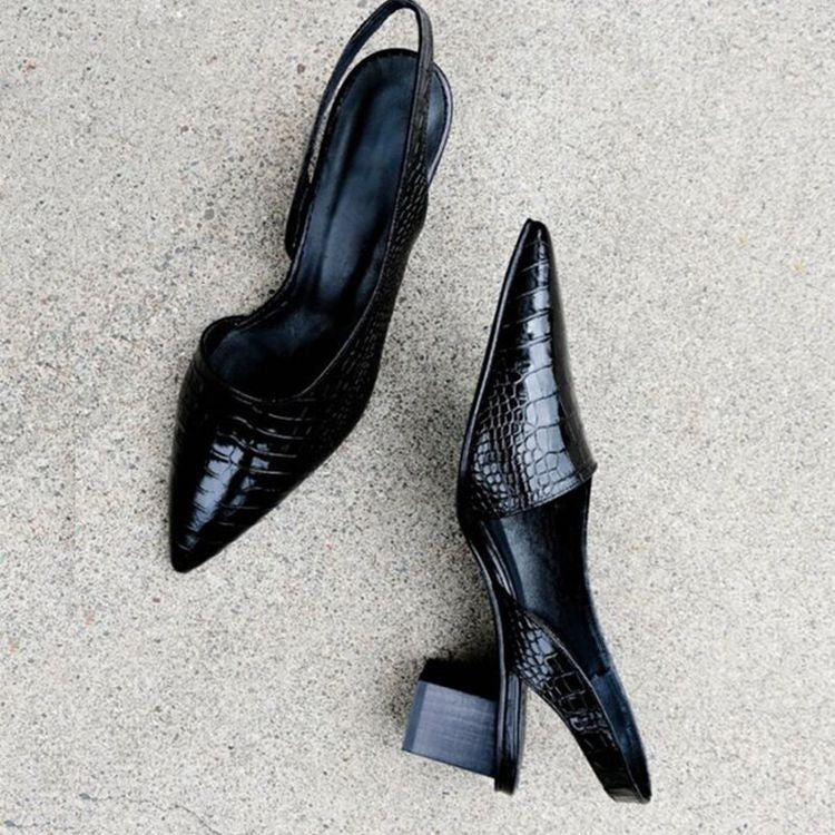 Pair of black crocodile embossed pointed toe slingback heels on a gray surface