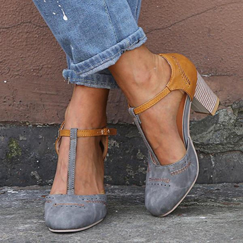 Women grey two-tone T-strap block heels with perforated toe detail, worn with cuffed jeans
