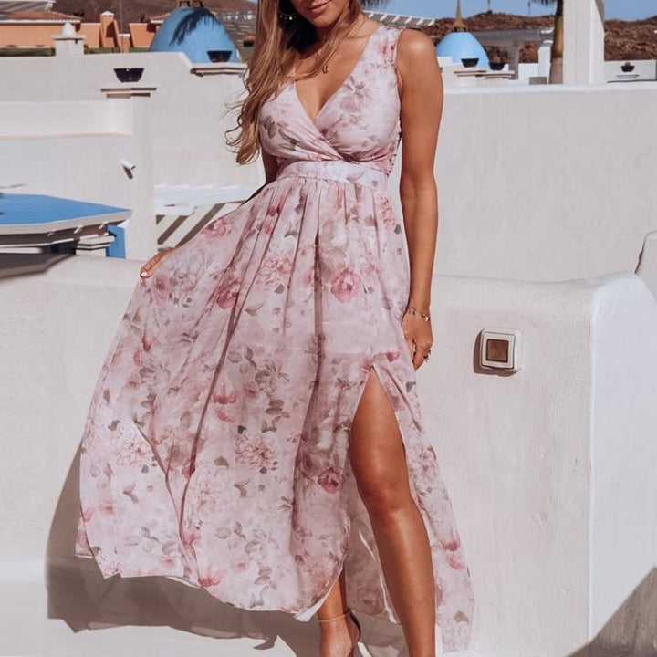 Women light pink floral maxi dress with wrap V-neck and sleeveless design, shown with side slit.
