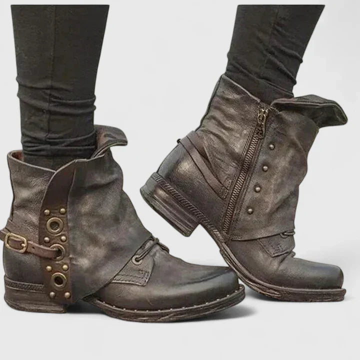 Women black textured ankle boots featuring a side zipper, buckle, and metal stud accents