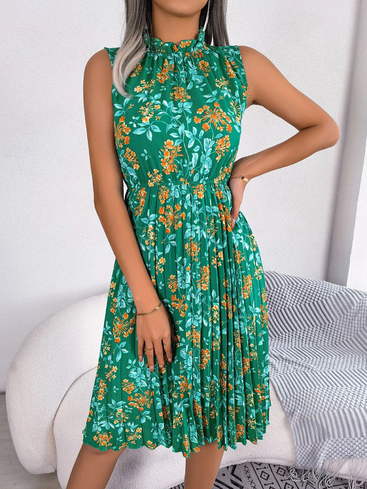 Women's green floral midi dress with orange flowers, high neck, and pleated skirt, model posing.