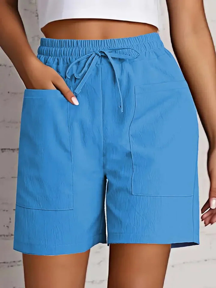 Women blue casual shorts with an elasticated waistband, drawstring closure, and prominent front patch pockets.