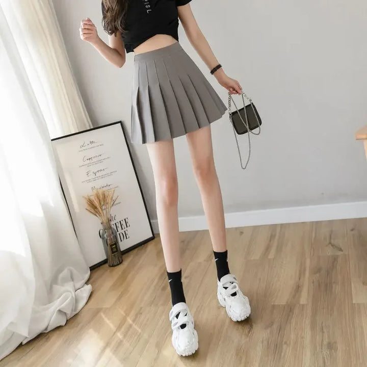 Women grey high waist pleated mini skirt, full body view, showing the mini length with sneakers.