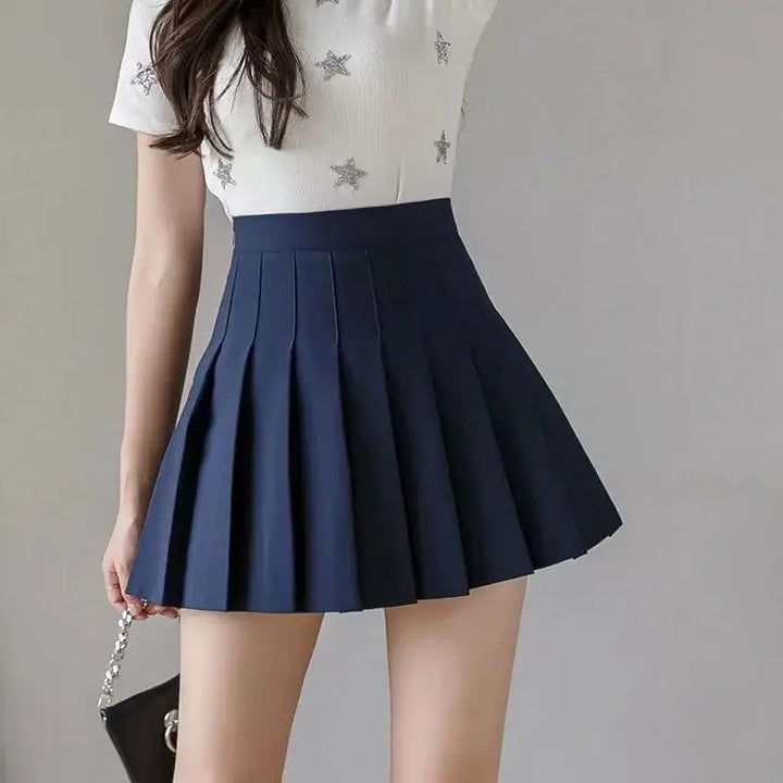 Women navy blue high waist pleated mini skirt, front view, paired with a white star-print top.
