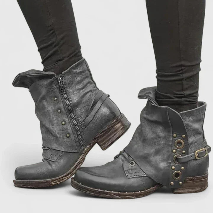 Women black vintage zipper ankle boots with buckle detail, shown on feet from side view