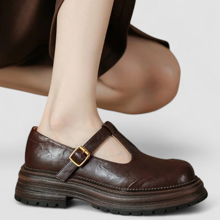 Women brown classic buckle mary jane platform shoe worn on a foot, side profile.