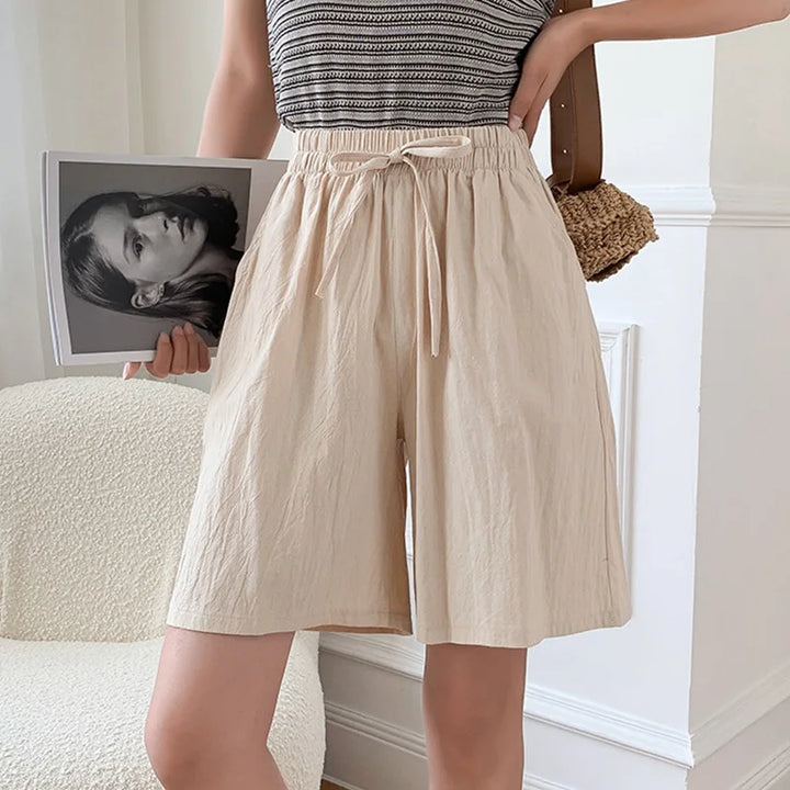 Women beige high waisted drawstring mini shorts with side pockets and elastic waist on model