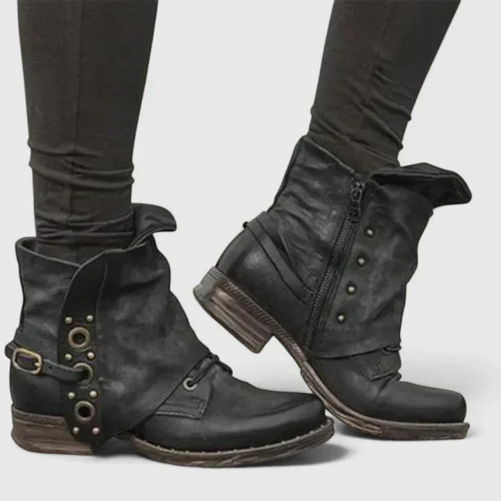 Women black distressed ankle boots with side zipper and decorative buckle, worn with black leggings