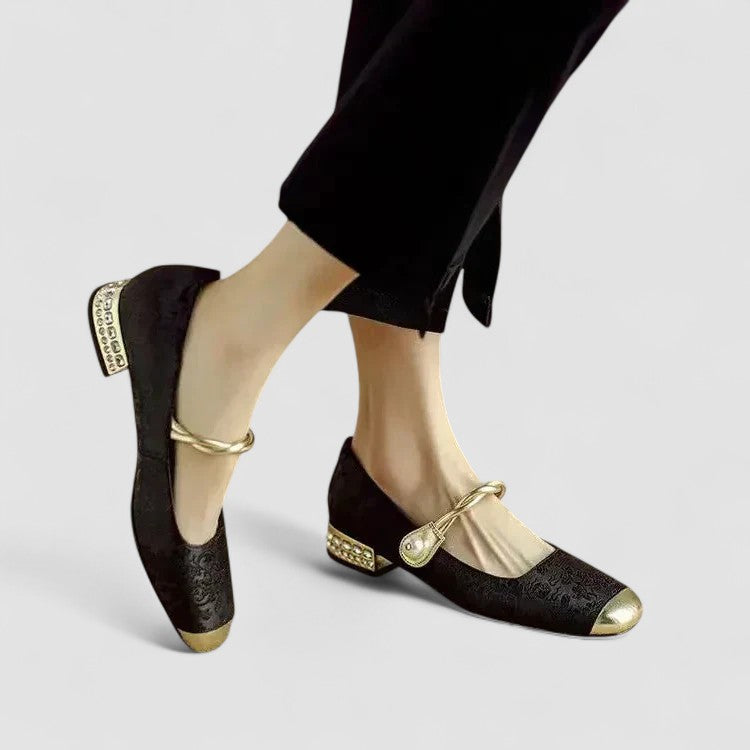 Women black Mary Jane shoes with square metallic toe cap and gold strap, shown on model's feet against a light background.