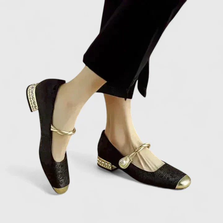 Women black Mary Jane heels with twisted strap, golden toe cap, and embellished block heel