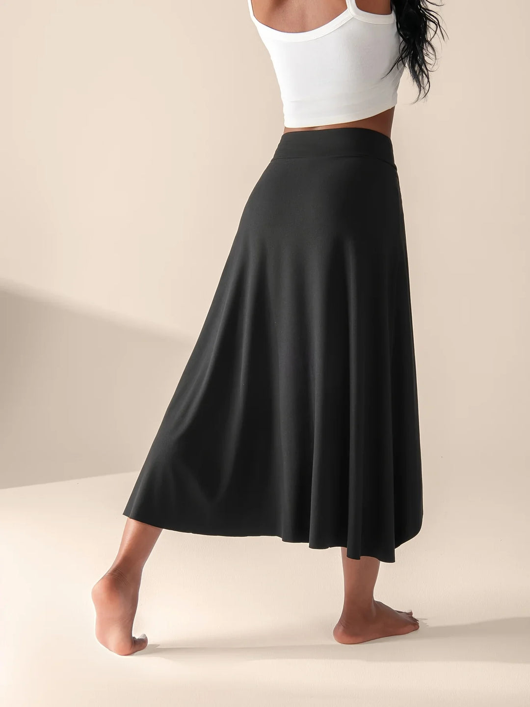Women black high waisted wrap midi skirt back view with flowing hemline