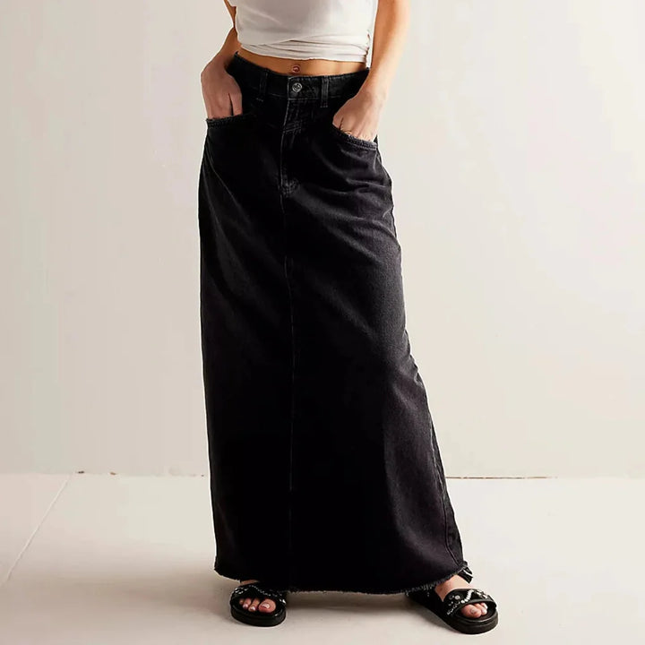 Women black denim maxi skirt with hands in pockets and a raw hem detail