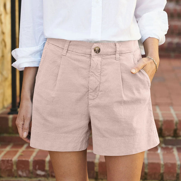 Women light pink high waisted pleated shorts with side pockets and a white shirt