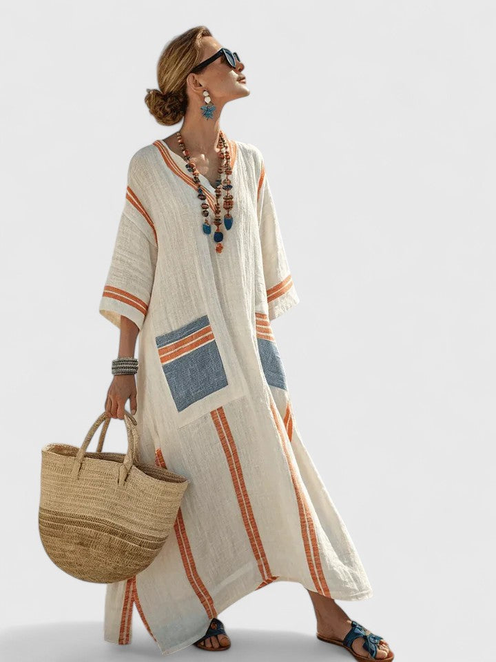 Women ivory and orange striped V-neck maxi dress with three-quarter sleeves and blue patch pockets, side view.