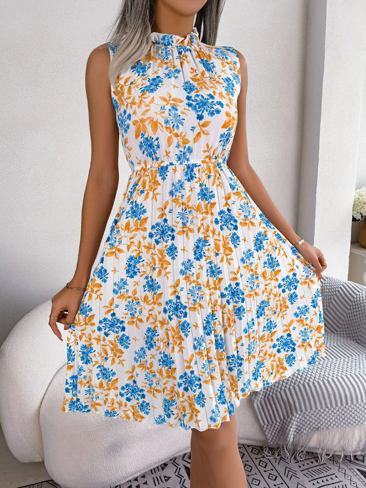 Women's white floral midi dress in blue and orange print, high neck, pleated skirt, model hands on skirt.