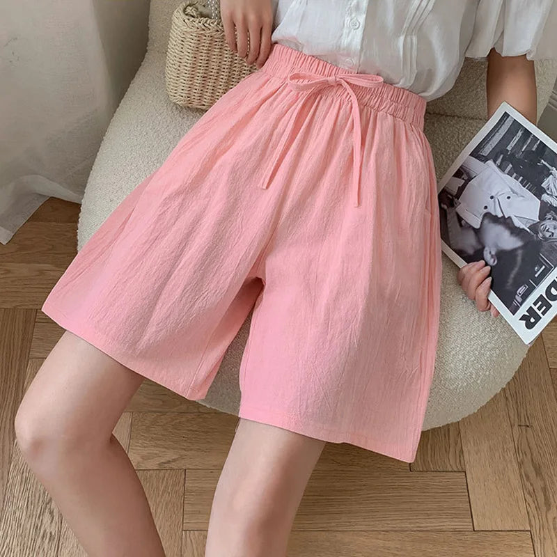 Women pink high waisted drawstring mini shorts with wide leg and elastic waist on model