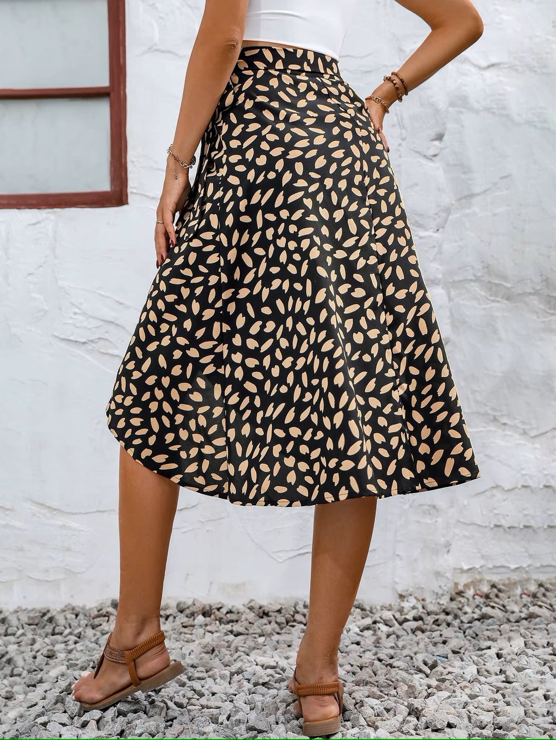 Women black floral print midi wrap skirt with side tie, back view, standing against a white wall.