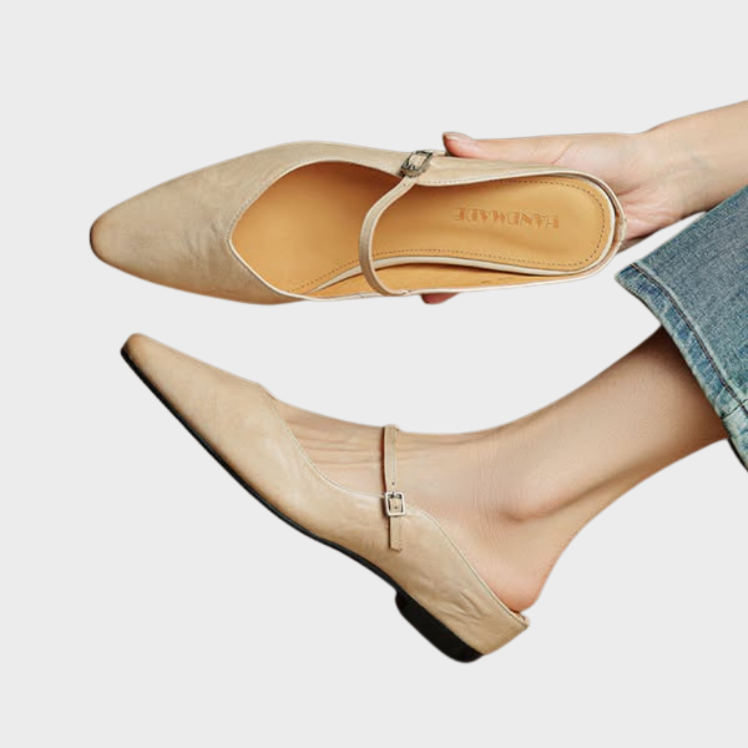 Women beige slip-on mules with pointed toe and buckle strap held in hand