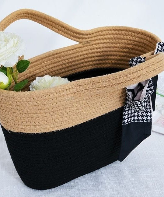 Close up view of the top handles and woven texture of the beige and black knit tote bag.