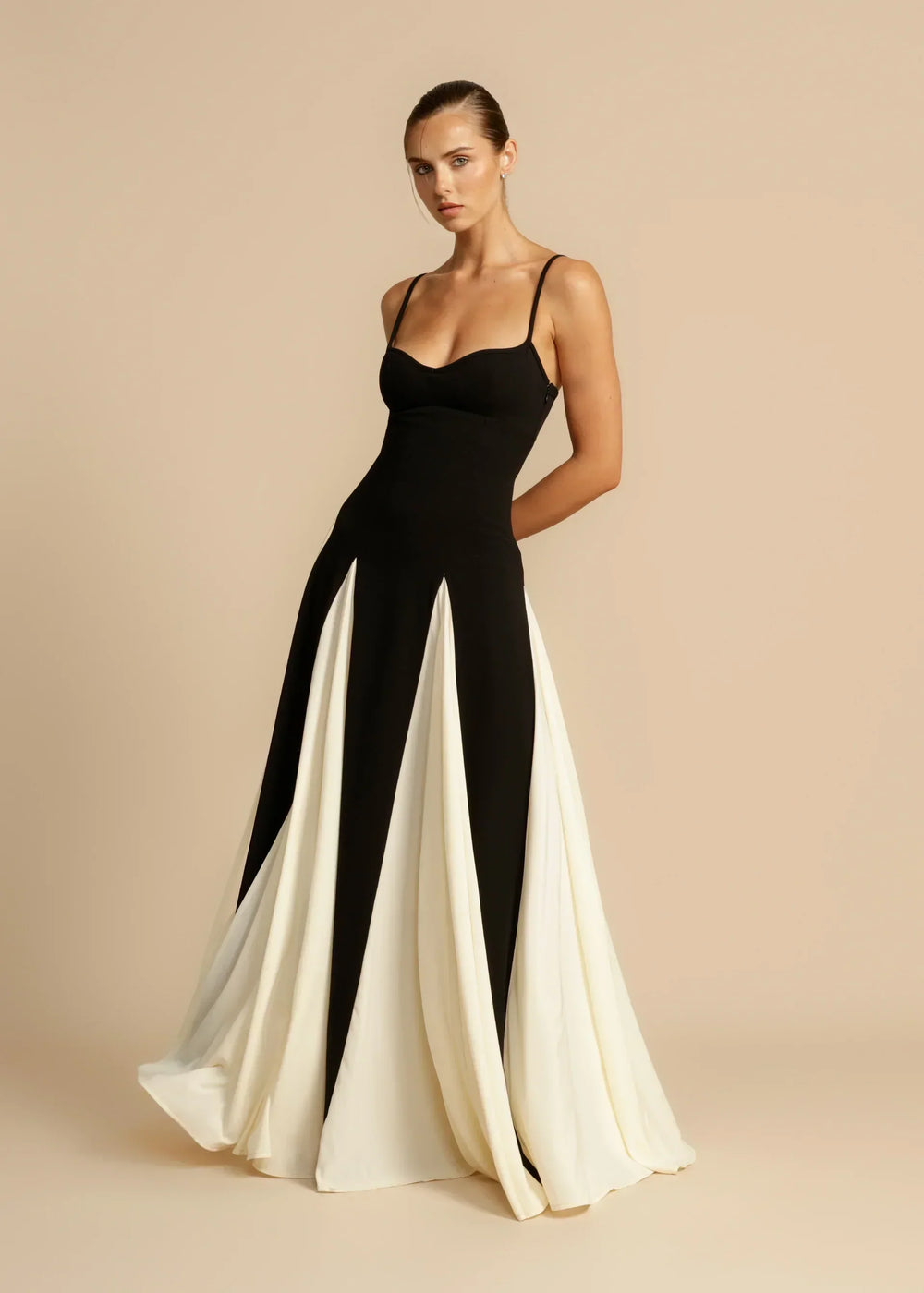 Women black and white sweetheart neck maxi dress with paneled skirt, side view with arm pose.