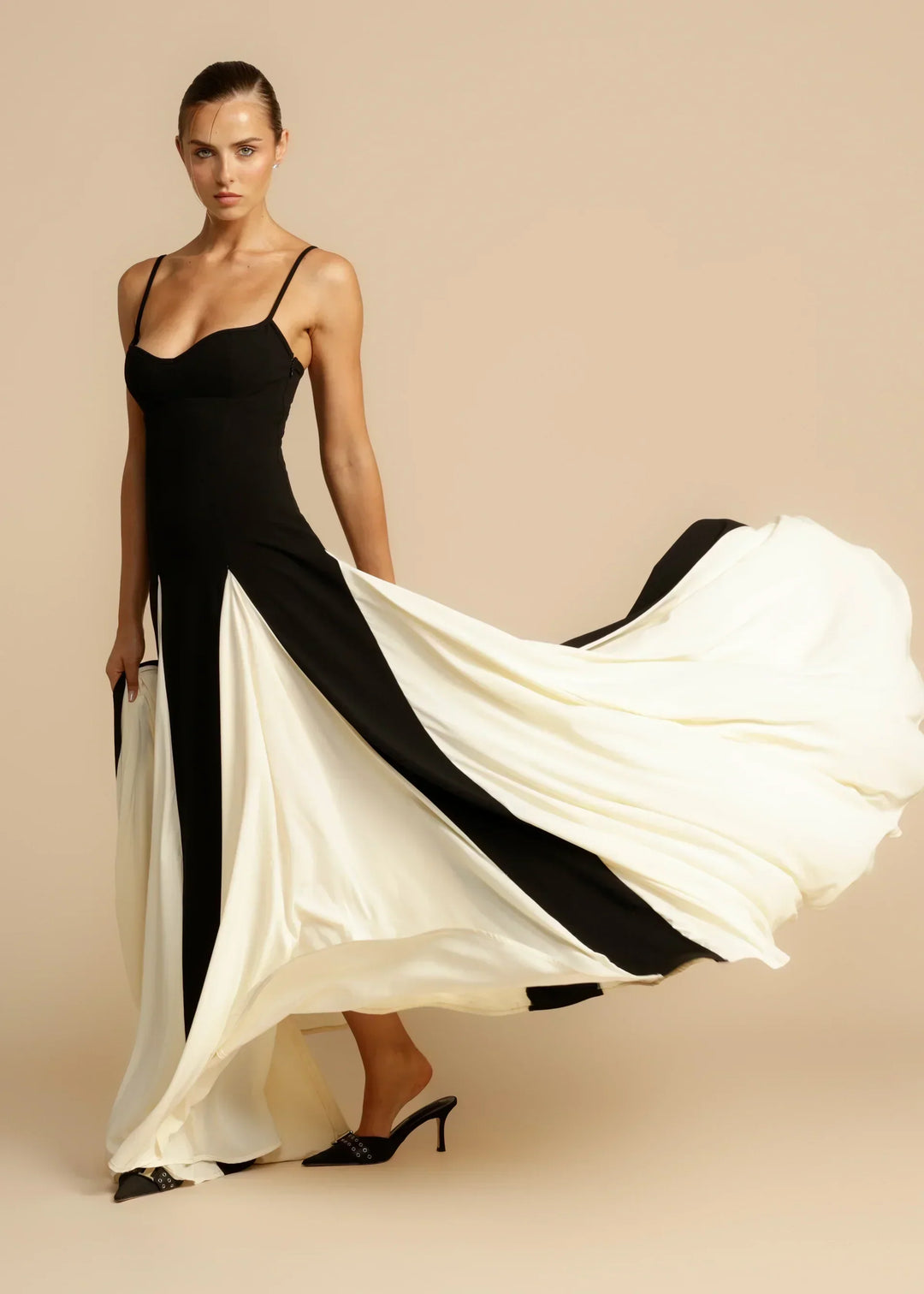 Women black and white maxi dress showing flowing skirt with panels and thin shoulder straps.