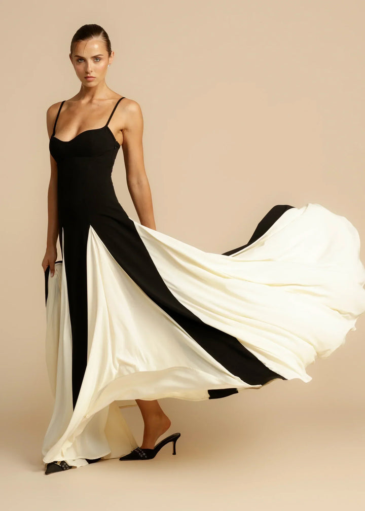 Women black and white maxi dress showing flowing skirt with panels and thin shoulder straps.