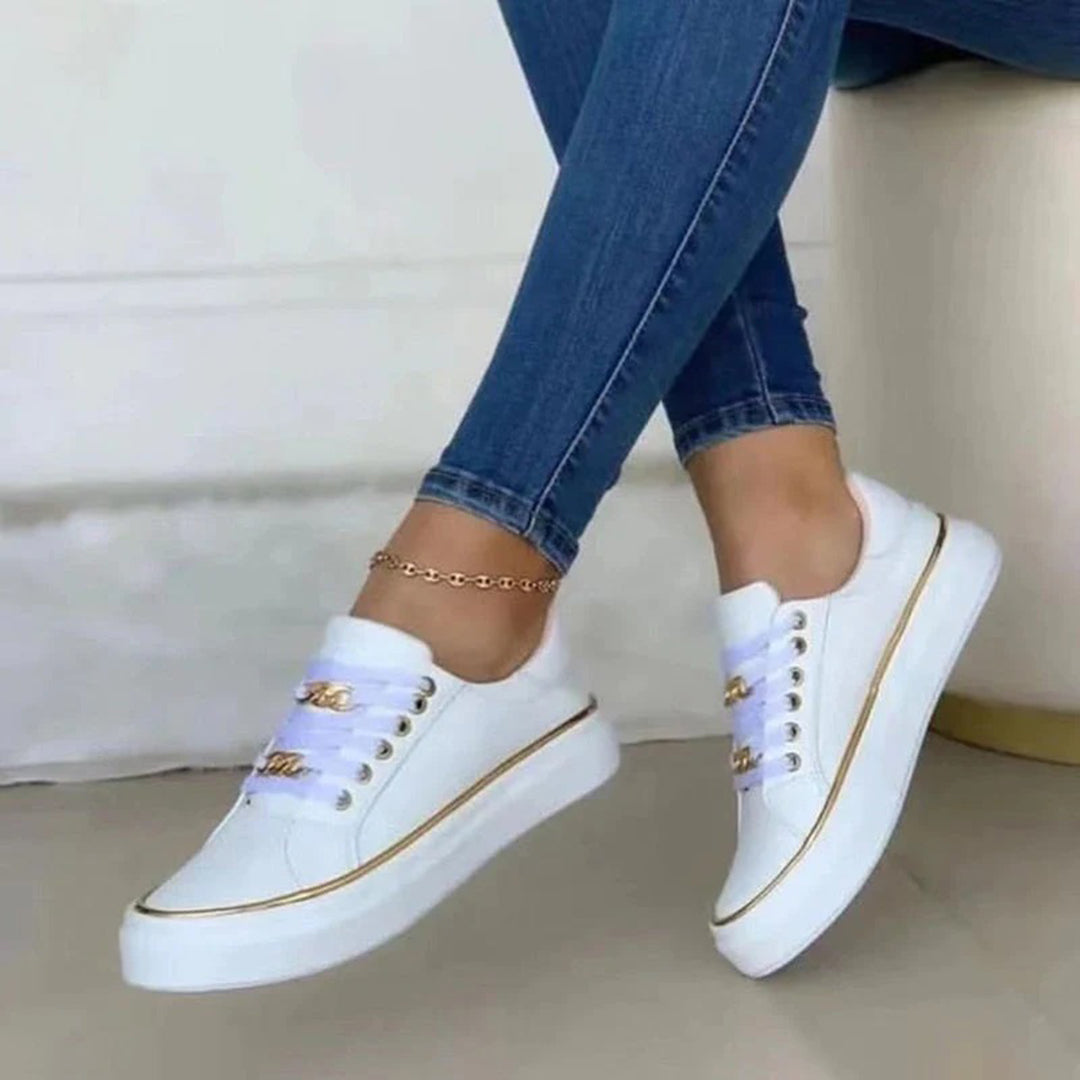 Women white low top sneakers with gold chain laces and tan ankle bracelet on model's feet