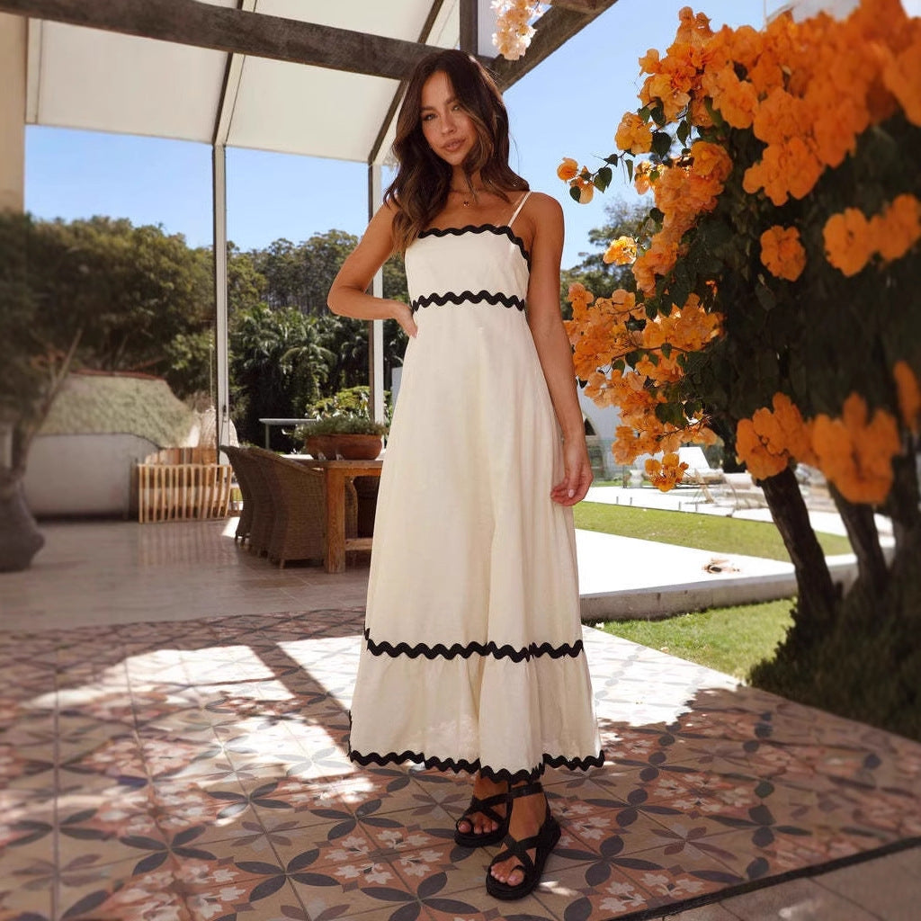 Women cream A-line spaghetti strap maxi dress with black scalloped trim, posed outdoors
