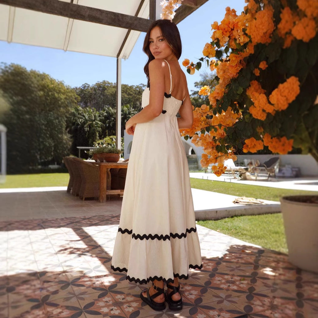 Women cream A-line spaghetti strap maxi dress with black scalloped trim, back view outdoors