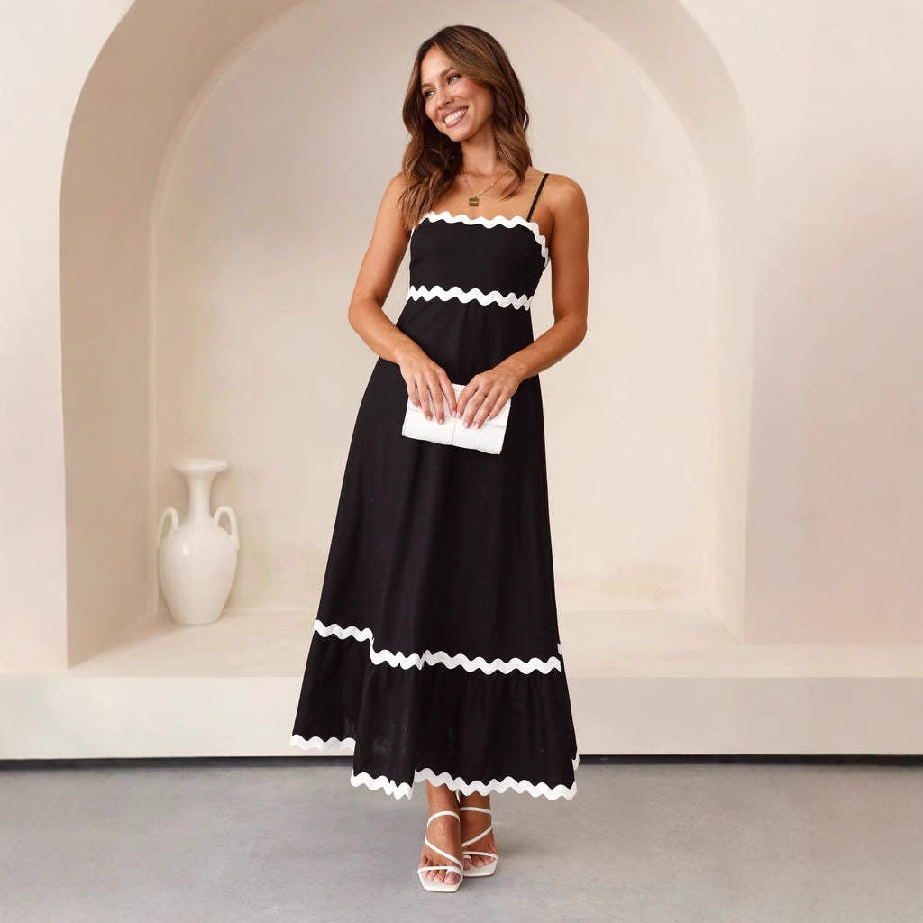 Women black A-line spaghetti strap maxi dress with white scalloped trim, posed indoors