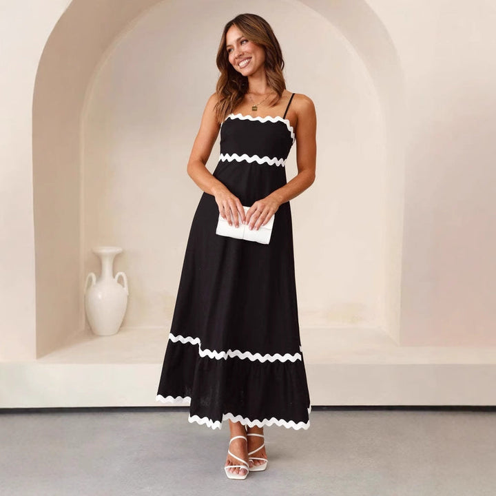 Women black A-line spaghetti strap maxi dress with white scalloped trim, posed indoors