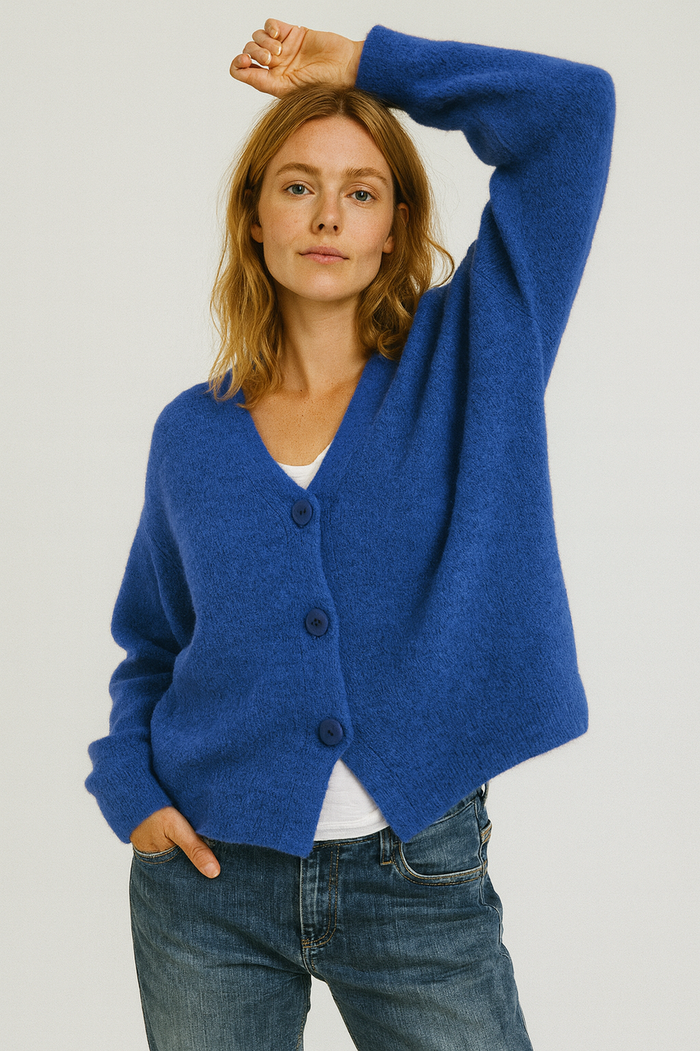 Women's blue V-neck knit cardigan with button-up front and long sleeves. Model with one arm raised to show sleeve length.