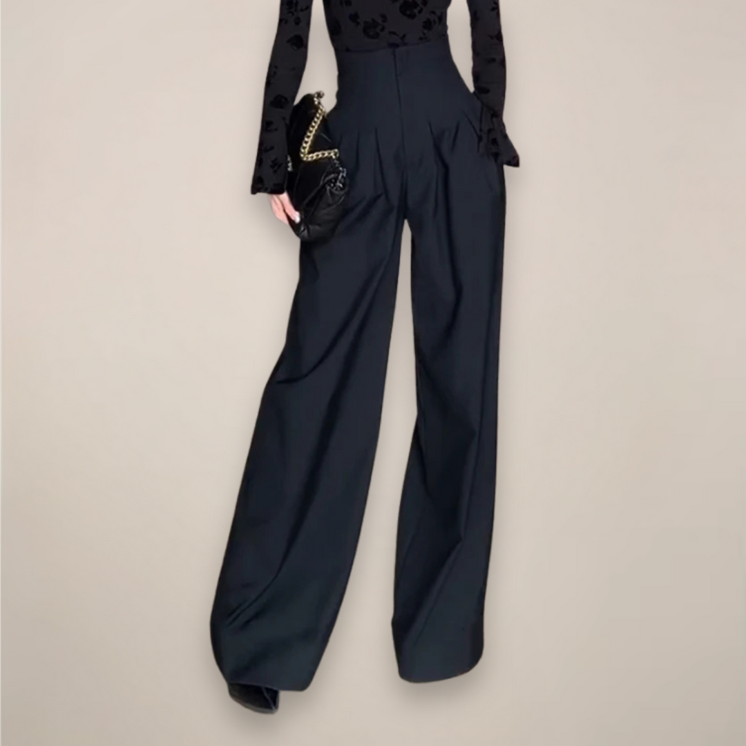 Women black high waisted wide leg slacks with front pleats, angled view with bag.