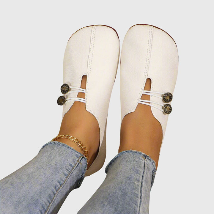 Women white slip on flats with button detailing and elastic cords worn with jeans