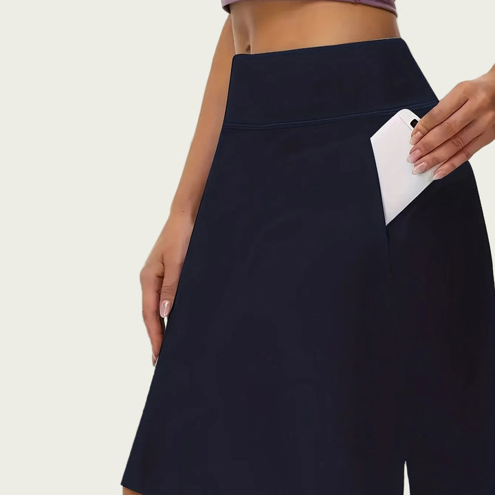 Women navy athletic skort with high waist and side pocket holding a phone.