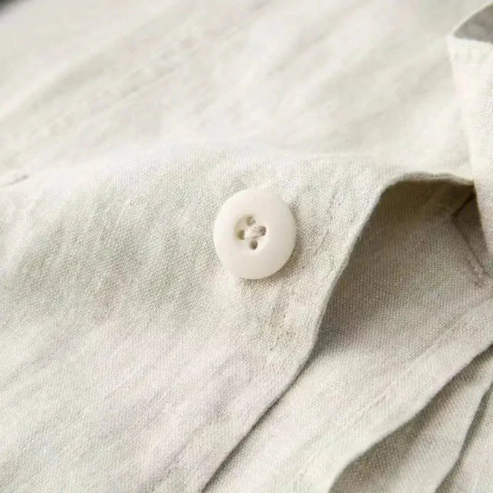 Close-up of beige linen fabric texture with white four-hole button on blazer