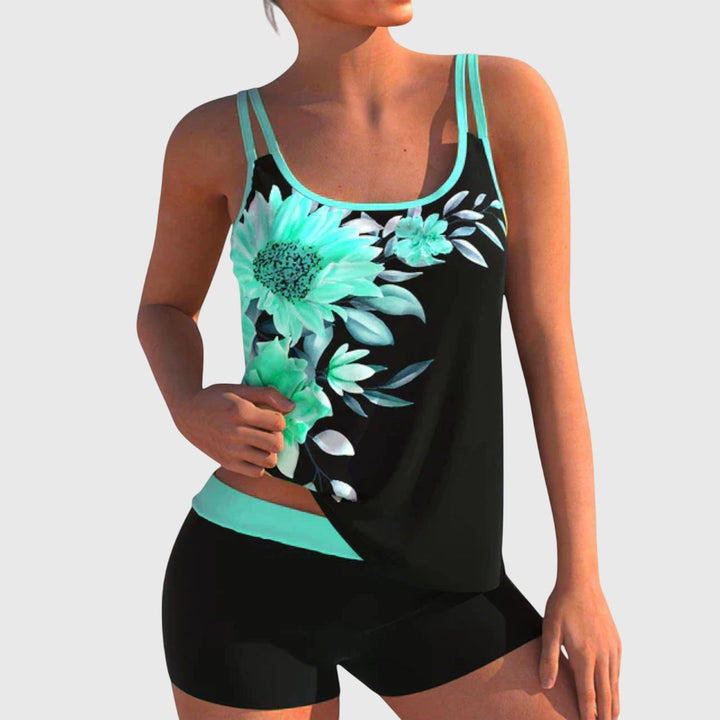 Black tankini top featuring turquoise daisy and floral print with cyan trim and black shorts