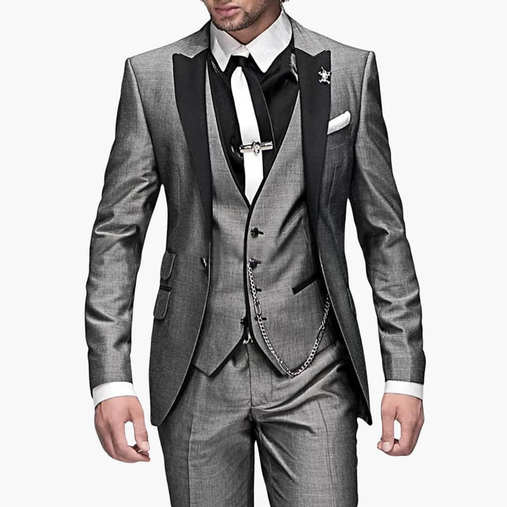 Charcoal gray three-piece suit with notch lapel blazer, black vest, and chain detail for formal events