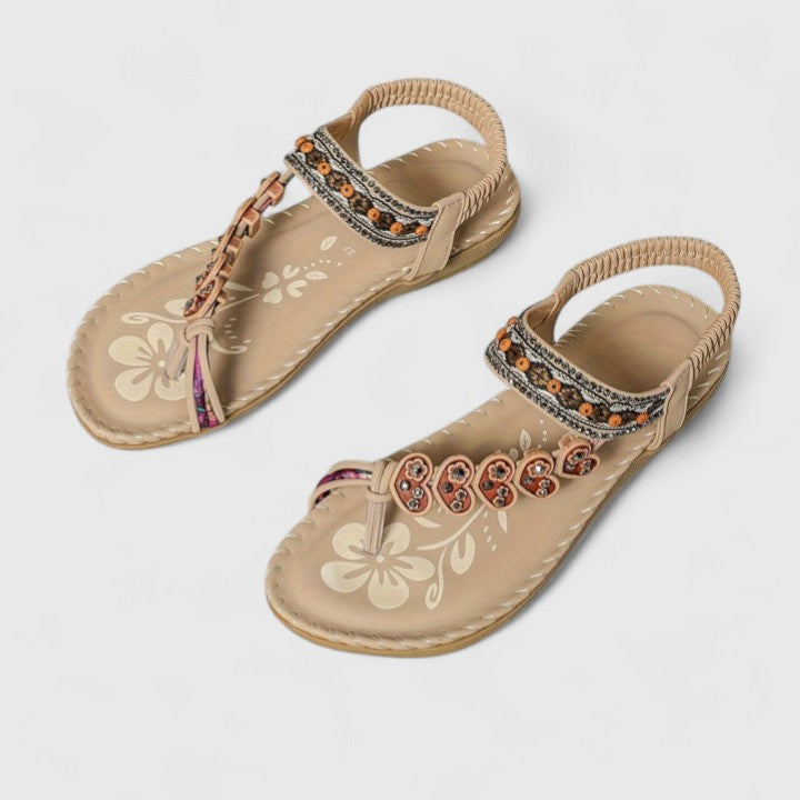 Pair of women's tan flat sandals with floral printed footbed and beaded straps