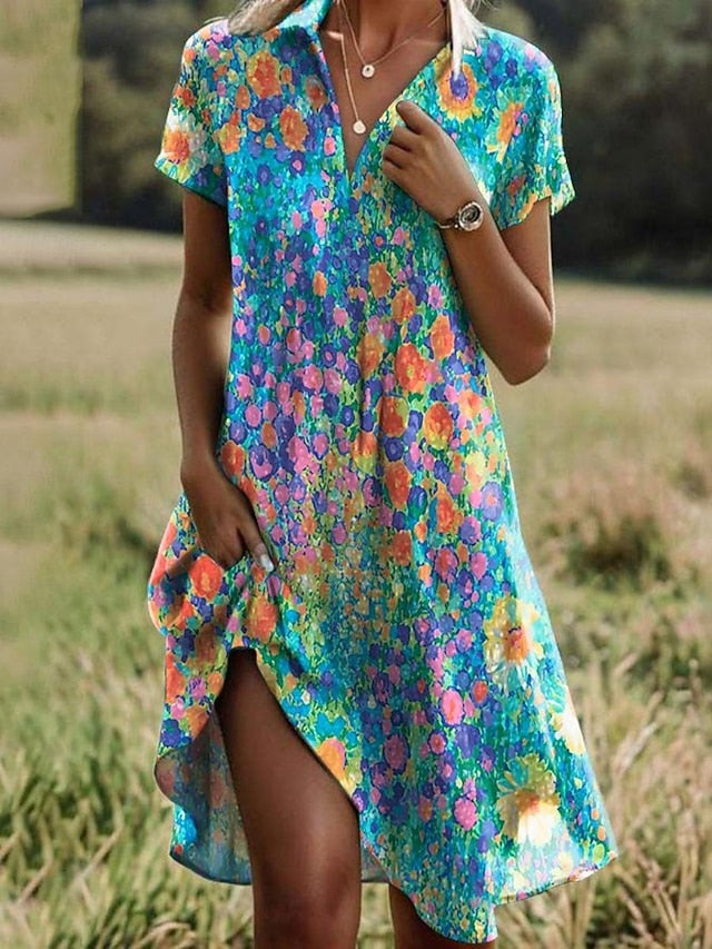 Women's floral short sleeve mini dress, close-up with leg and fabric detail in grassy field