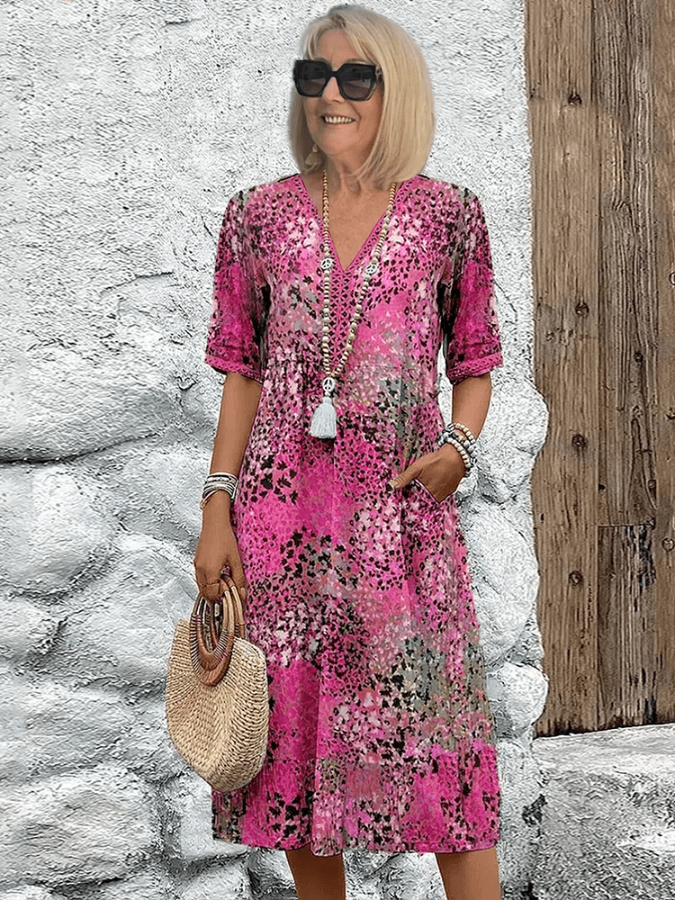 Women's pink multi-color printed midi dress with V-neck, short sleeves, and tiered hem detail.