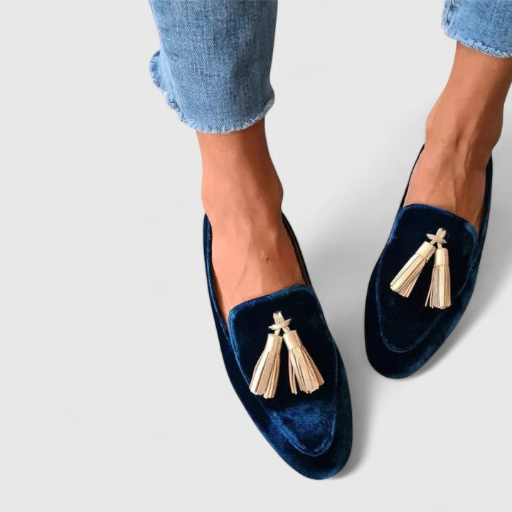 Women wearing blue velvet loafers with gold tassels, shown with light wash jeans