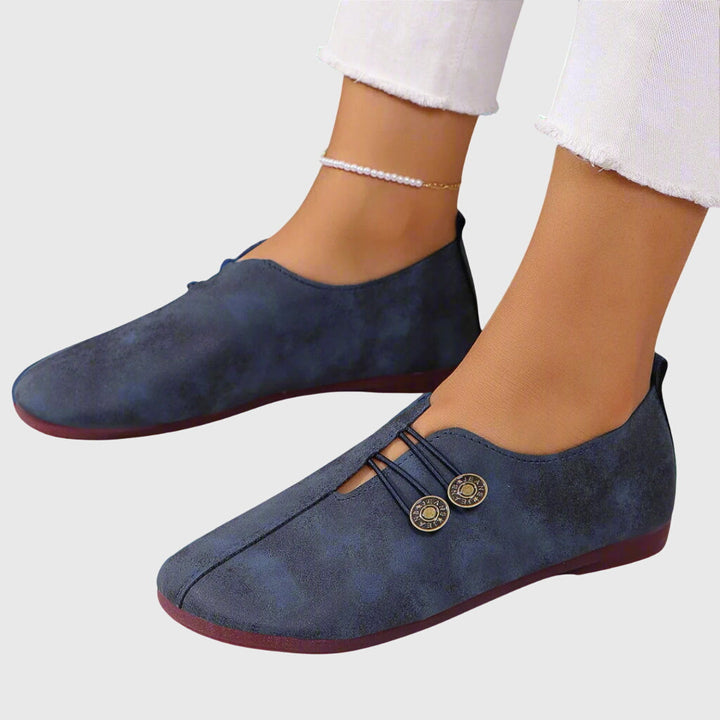 Women blue slip on flats featuring button detail and rounded toe from side angle
