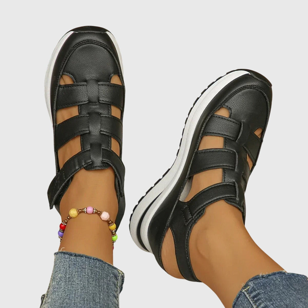 Women's black platform sandals with cut-out strap design on both feet, top down view