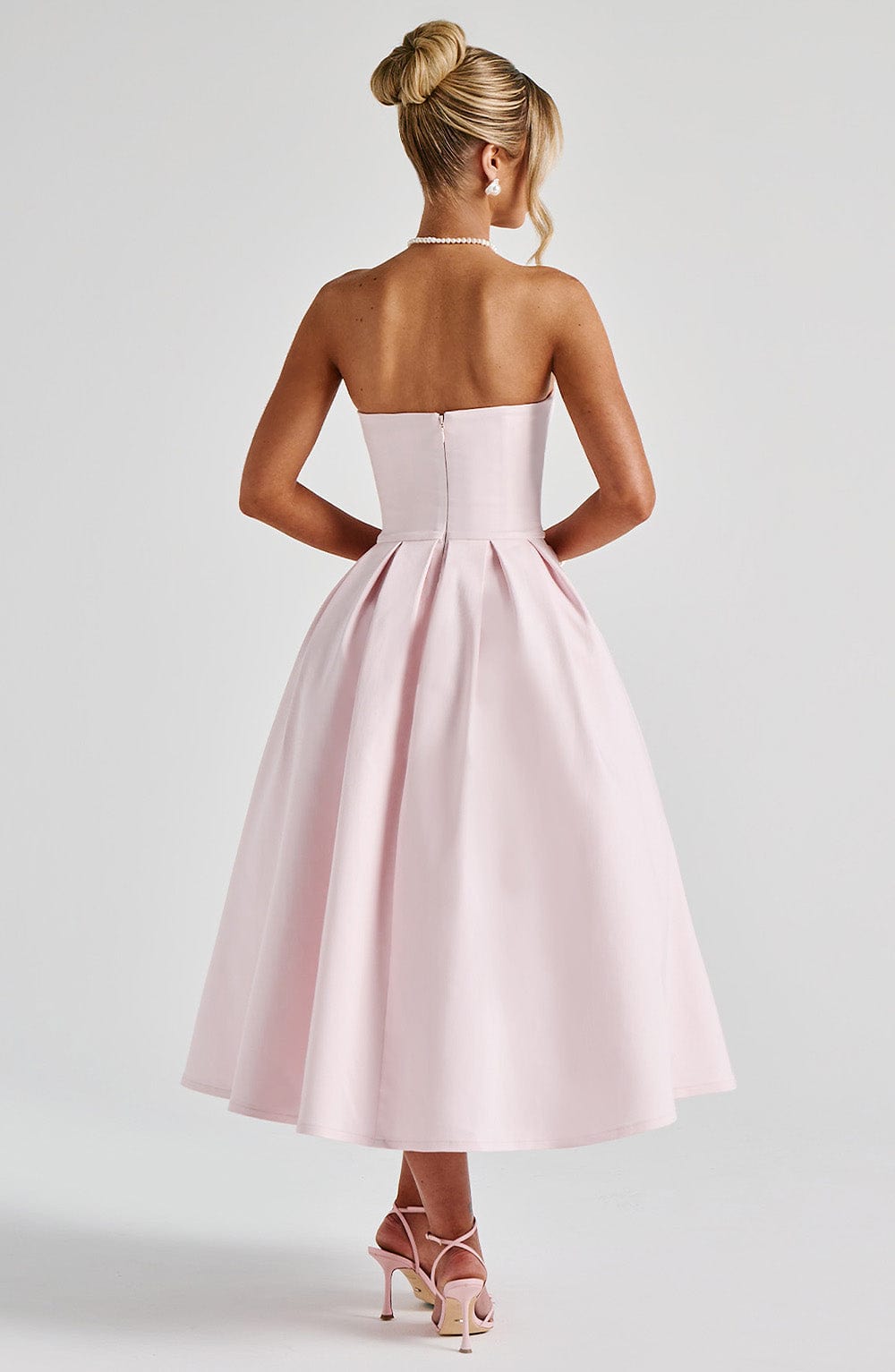 Women light pink strapless pleated midi dress back view showing zipper
