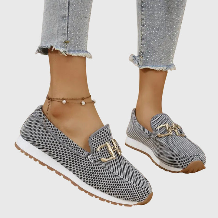 Women grey slip on buckle loafers with mesh upper and brown outsole, angled view