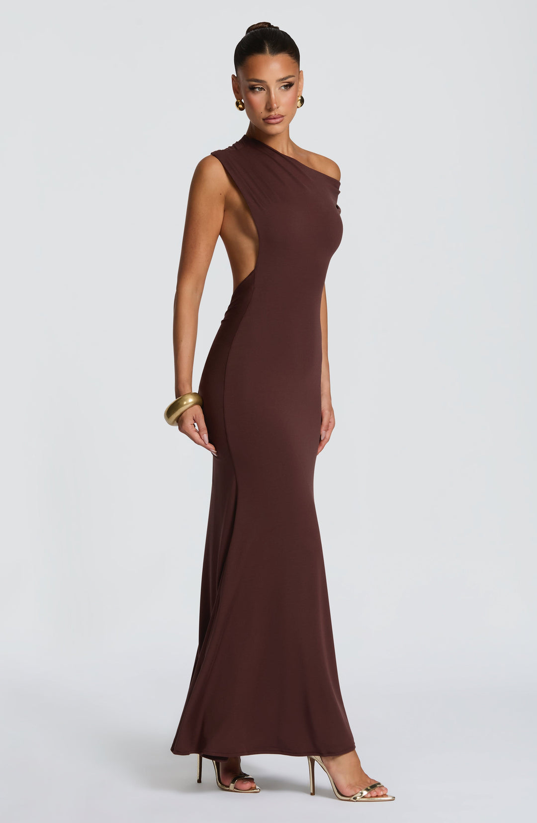 Women plum brown backless one shoulder maxi dress showing draped detail and side cutout, side view