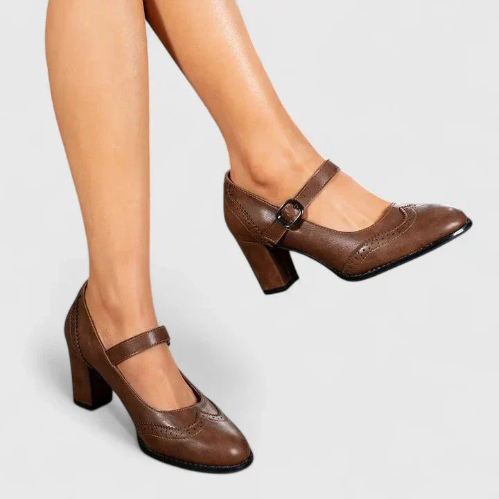 Women brown Mary Jane block heels with a rounded toe and buckled strap on a model's feet.