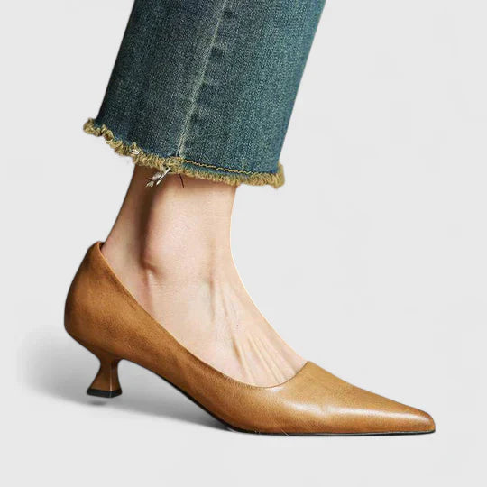 Women's tan pointed toe low heel pumps with a flared heel, shown with blue jeans.