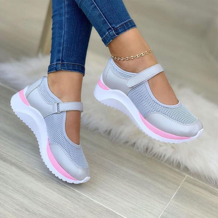 Women's light gray mesh Mary Jane sneakers with pink sole accents, shown from a slightly elevated angle on a model's feet.